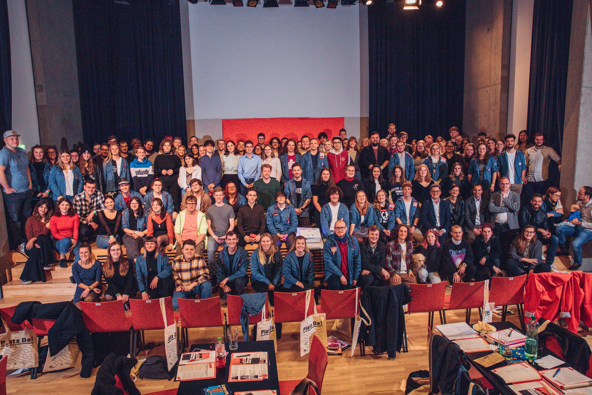 Gruppenfoto der Landeskonferenz der Sozialistischen Jugend Oberösterreich. Es sind über 100 junge Menschen auf der Bühne in mehreren Reihen aufgestellt. Viele tragen ein Blauhemd.