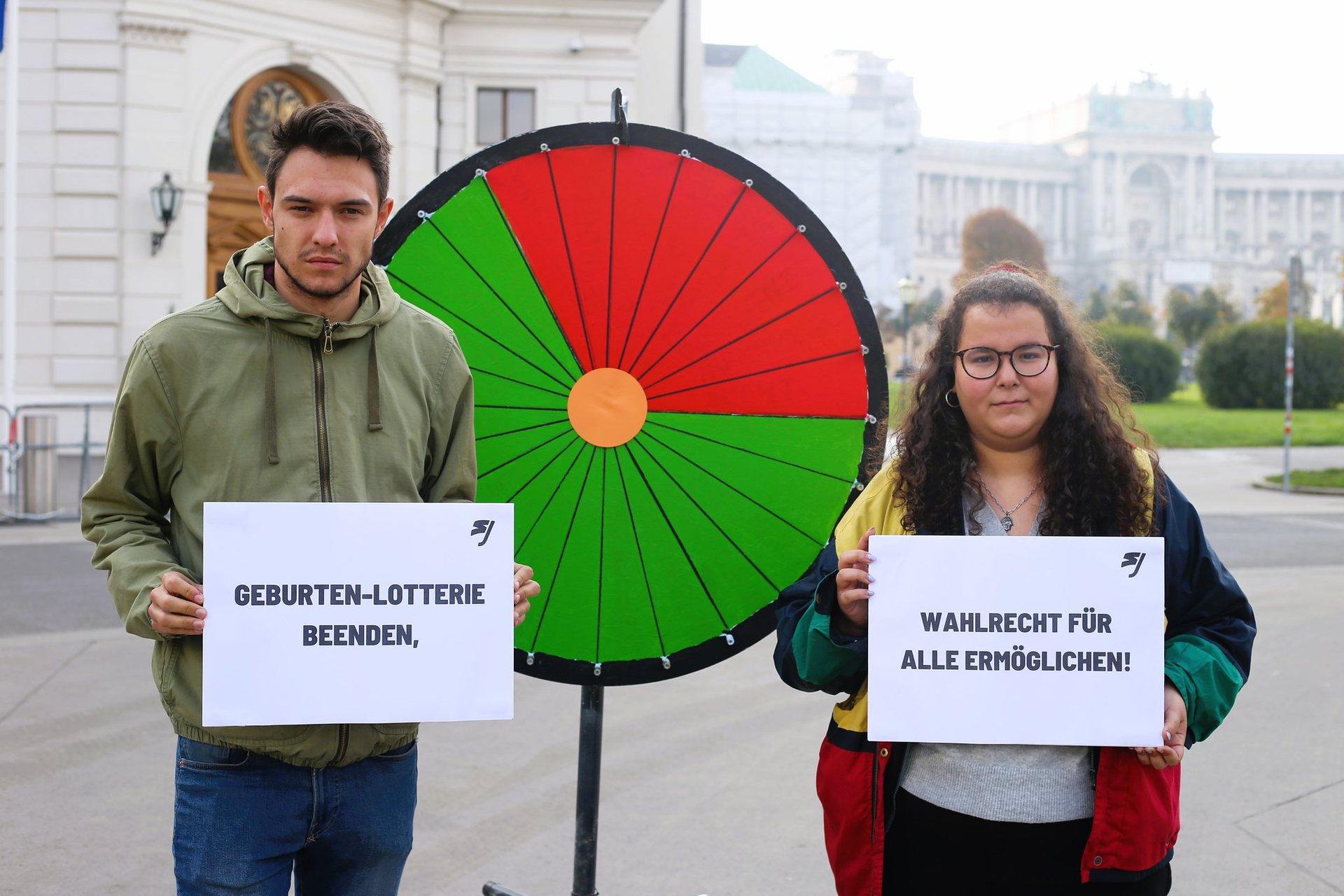 Paul Stich und Rihab Toumi protestieren mit eienm Glücksrad für eine Reform des Staatsbürgerschaftsrechts