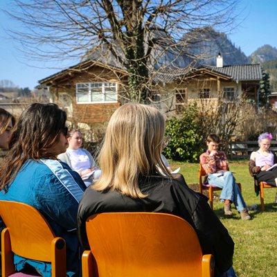 ein paar junge Frauen sitzen in einem Sesselkreis im Freien