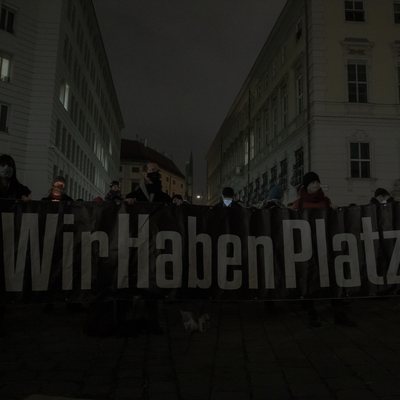 Lichtermeer für eine menschliche Asylpolitik. Personen im Vordergrund halten ein Transparent. Auf dem steht oben: Wir haben Platz!