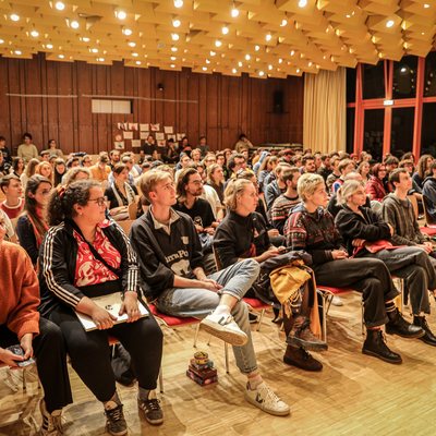 viele Jugendliche sitzend in Reihen in einem großen Saal mit Blick zur Bühne