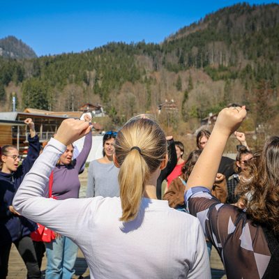 junge Frauen singen mit erhobener Faust; zu sehen von hinten
