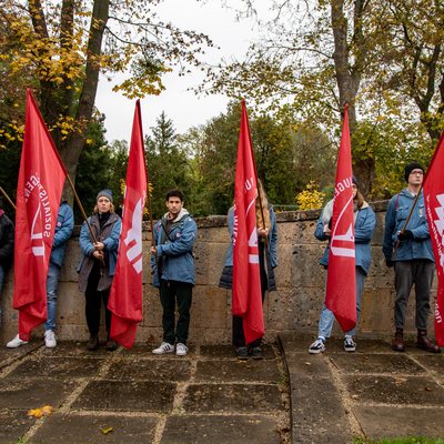 Jugendliche halten beim Novembergedenken eine Fahne vor sich, nach unten gesenkt. Sie tragen ein Blauhemd. 